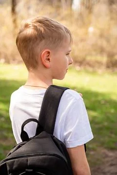 Back view of a boy with backpack walking on a path in the park Stock Photos