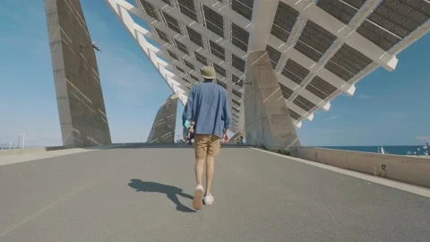 Back view of a boy walking with his skate board under his arm in a city 스톡 동영상 143562178