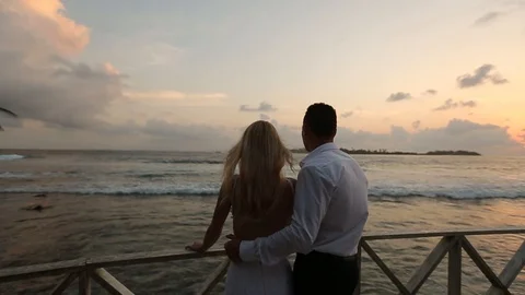 Back view of bride and groom enjoying sunset on tropical beach near balustrade Stock Footage 95495165