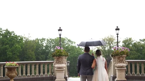 Back view. Bride and groom under an umbrella during the rain. Stock Footage 129114660
