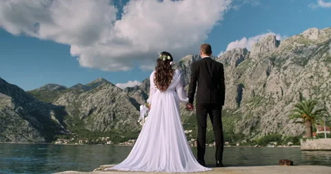 Back view of bride in beautiful white dress and groom on mountain background Stock Footage 130581245