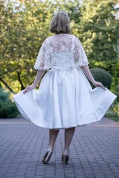 Back view of a bride holding the sides of her flowing tea-length wedding dress,  Stock Photos