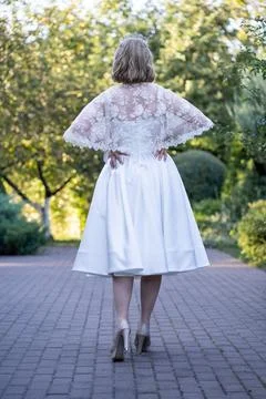 Back view of a bride standing confidently with hands on hips, showcasing a lace  Stock Photos