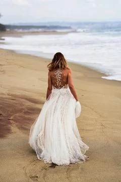 Back view of a bride in a white wedding dress on the beach Stock Photos