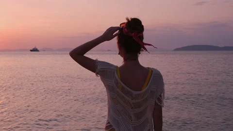 Back view of a brunette girl standing and enjoying the orange sunset Stock Footage