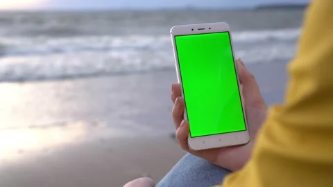 Back view of brunette holding chroma key green screen smartphone watching Stock Footage 132085306