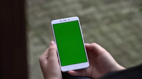 Back view of brunette holding chroma key green screen smartphone watching Stock Footage 132161610
