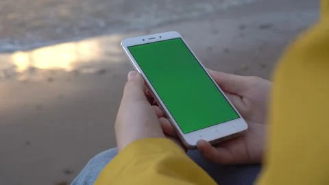 Back view of brunette holding chroma key green screen smartphone watching Stock Footage 132188175