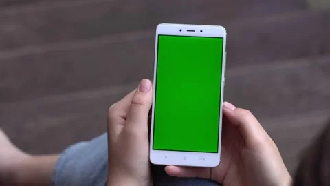 Back view of brunette holding chroma key green screen smartphone watching Stock Footage 132683206