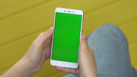 Back view of brunette holding chroma key green screen smartphone watching Stock Footage 132683249