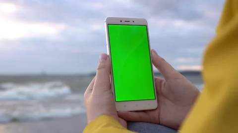 Back view of brunette holding chroma key green screen smartphone watching Stock Footage 133100800