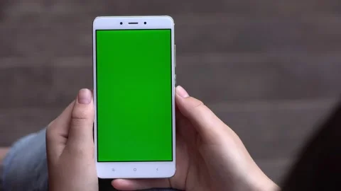 Back view of brunette holding chroma key green screen smartphone watching Stock Footage 133260533