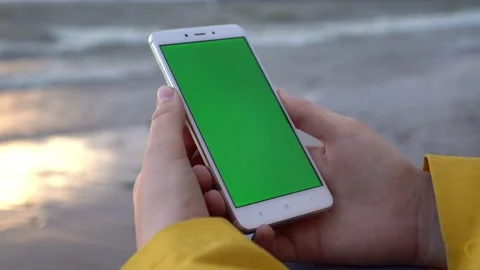 Back view of brunette holding chroma key green screen smartphone watching Stock Footage 133517440