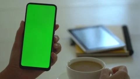 Back view of brunette holding chroma key green screen smartphone watching Stock Footage 139903576