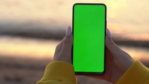 Back view of brunette holding chroma key green screen smartphone watching Stock Footage 140583547