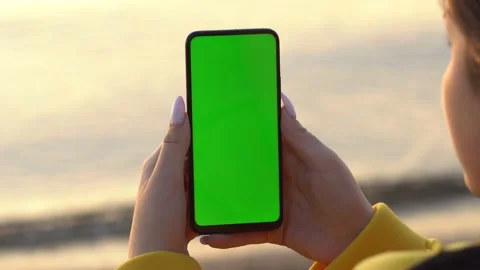 Back view of brunette holding chroma key green screen smartphone watching Stock Footage 140696131