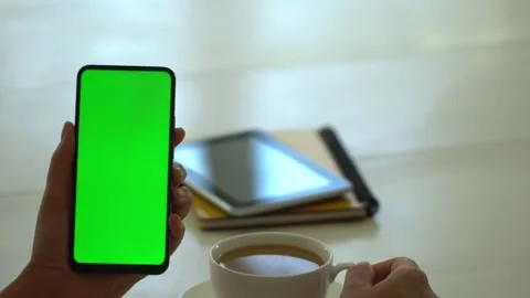 Back view of brunette holding chroma key green screen smartphone watching Video stock 140947558