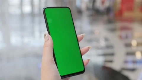 Back view of brunette holding chroma key green screen smartphone watching Stock Footage 208888445