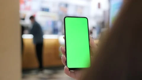 Back view of brunette holding chroma key green screen smartphone watching Stock Footage 209819978