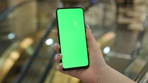 Back view of brunette holding chroma key green screen smartphone watching Stock Footage 209820537