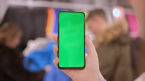 Back view of brunette holding chroma key green screen smartphone watching Stock Footage 245122355