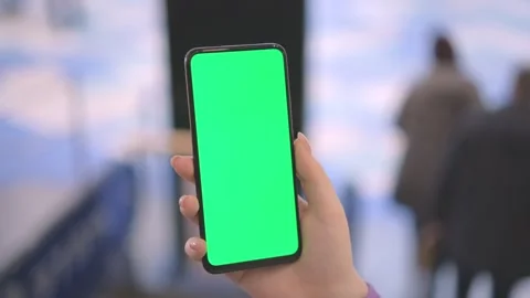 Back view of brunette holding chroma key green screen smartphone watching Stock Footage 245817834