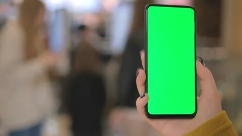 Back view of brunette holding chroma key green screen smartphone watching 스톡 동영상 251014570