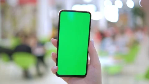 Back view of brunette holding chroma key green screen smartphone watching Stock Footage 257797361