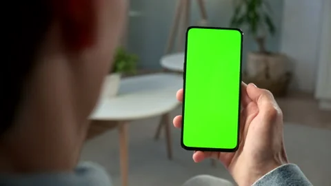 Back View of Brunette Man Holding Chroma Key Green Screen Smartphone Watching Stock Footage 133219317
