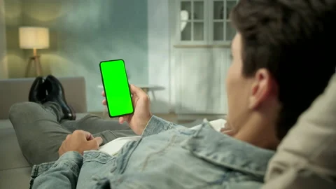 Back View of Brunette Man Holding Chroma Key Green Screen Smartphone Watching Stock Footage 133230398