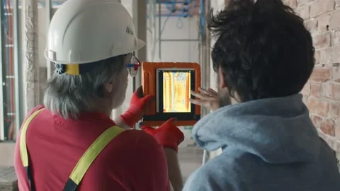 Back view of builder and architect check construction site with thermal camera Stock Footage 133637336