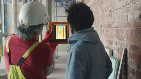 Back view of builder and owner check heat insulation with thermal camera Vidéo 133638956