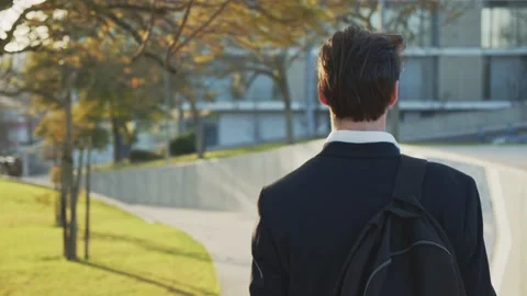 Back view to the businessman with a backpack walks quickly down the street... Stock Footage 235377896