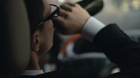 Back view of businessman drinking alcohol in car before driving home, problems Stock Footage 98759908