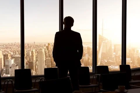 Back view of a businessman looking through window before meeting in New York Stock Photos