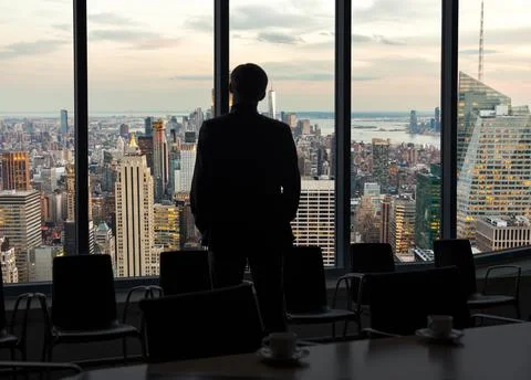 Back view of a businessman looking through window before meeting in New York Stock Photos