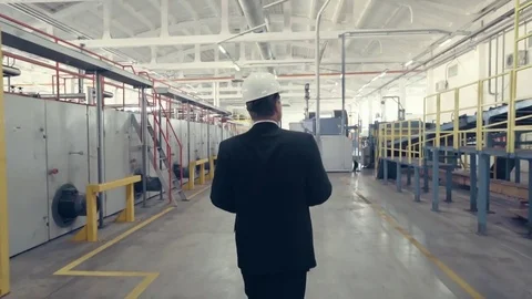 Back view of businessman walking through factory Stock Footage 74897109