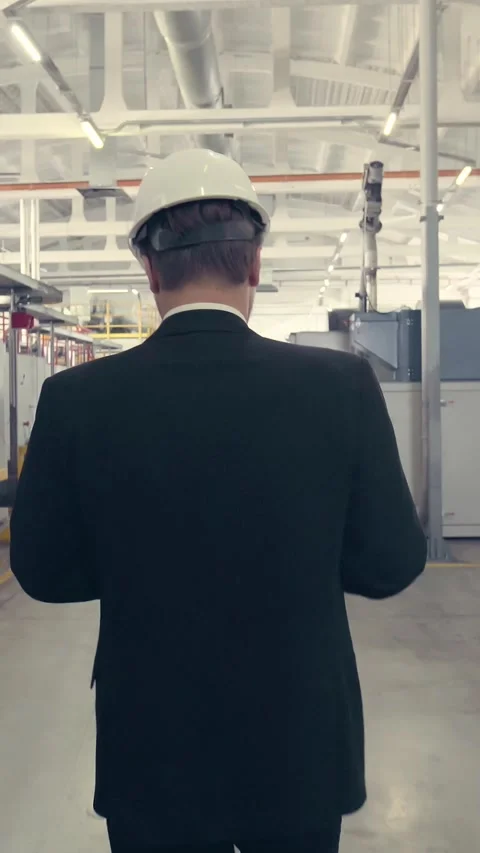 Back view of businessman walking through factory Stock Footage 227283440