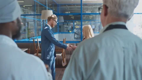 Back view of cafe staff watching young manager welcoming new employee with Stock Footage 135226660