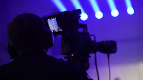 Back view of camera operator recording stage presentation using broadcast equ Stock Footage 322153382