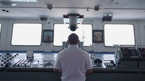 Back view of captain of the cargo ship standing by the dashboard and steering Stock Footage