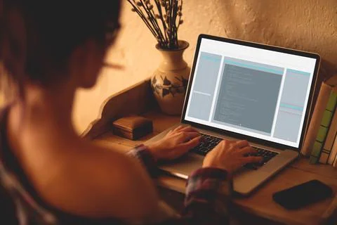 Back view of caucasian female programmer sitting at desk, using laptop with 스톡 사진
