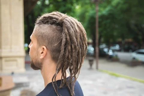 Back view of a caucasian man with dreadlocks and sidecut on a summer street Stock Photos