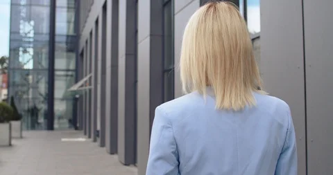 Back view on the Caucasian young blonde woman in business style walking outside Stock Footage 120201348