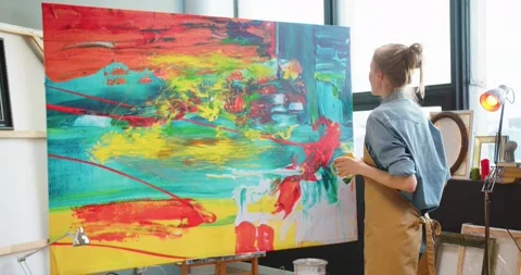 Back view of Caucasian young pretty talented woman painter standing in own Stock Footage 149576770