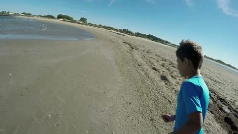 Back view of the cheerful boy running on the beach on a background of the sea Stock Footage 136366693