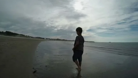 Back view of the cheerful boy walking on the beach on a background of the sea Stock Footage 136455841