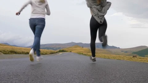 Back view of cheering young female friends running on a mountain road express Stock Footage 86216468