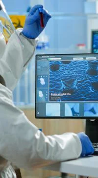 Back view of chemist man in coverall typing on computer analysing vaccine Stock Photos