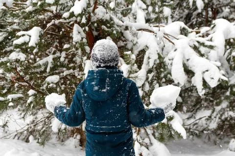 Back view of child boy in winter forest in snowstorm. Kid holding snowball. A Stock Photos